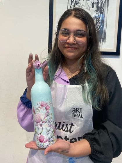 A participant proudly displays the beautiful floral decoupage bottle she created. It's a wonderful handmade gift or piece of home decor.