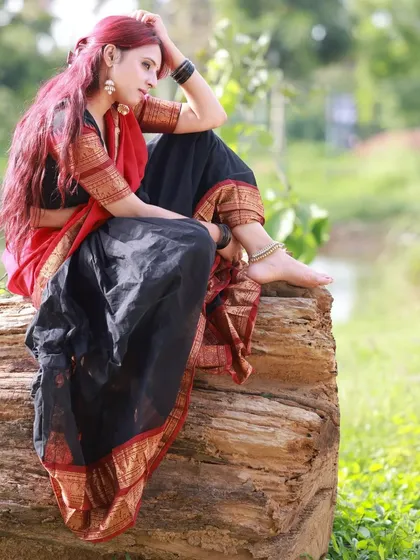 A profile shot of the model sitting on a log by the water. This serene and picturesque scene perfectly complements the traditional aesthetic of the half-saree.