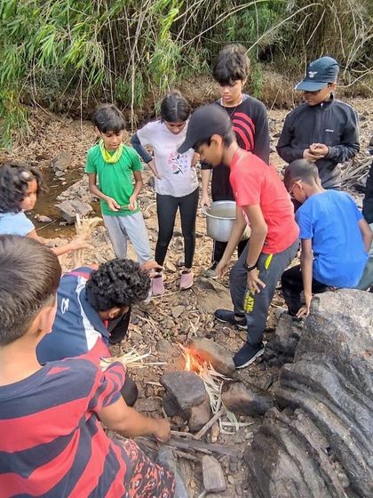 A group of young boys works together to build and light a fire for cooking at our Barapole camp.