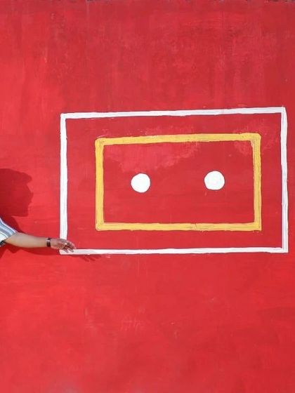 A quirky and creative pre-wedding shot against a bright red wall. This kind of playful and artistic photo shows the fun side of the couple's personality.