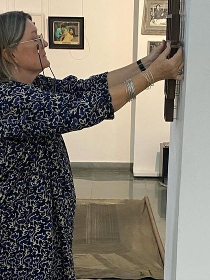 The artist herself, Clare Arni, making adjustments to a framed piece during the installation.