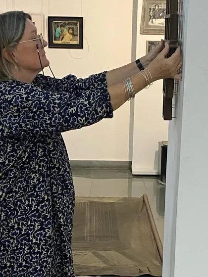 The artist herself, Clare Arni, making adjustments to a framed piece during the installation.