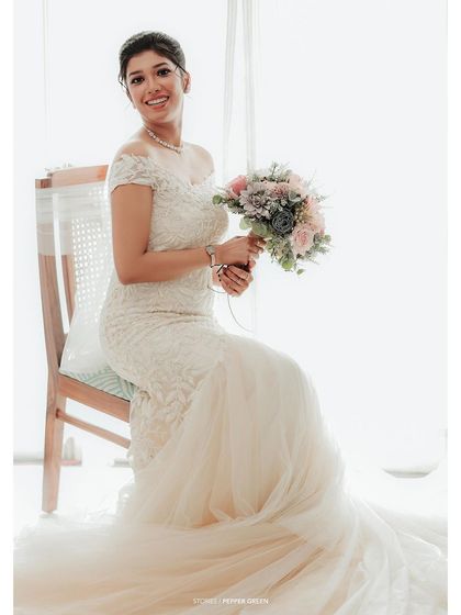 A full-length portrait of the bride seated gracefully, her beautiful gown and train spread around her.