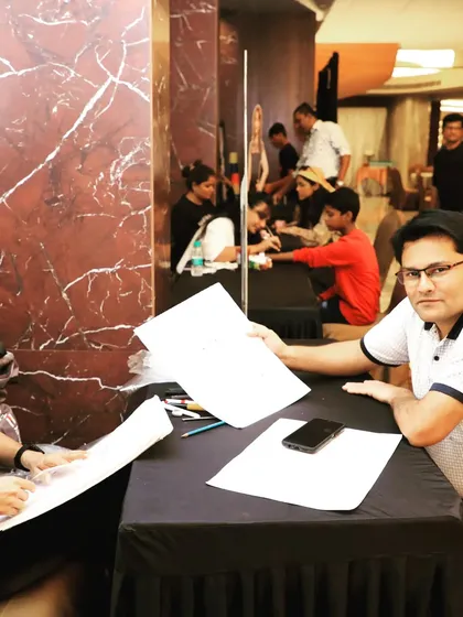 A caricature artist proudly displaying his work. We coordinate with a variety of talented artists to provide unique entertainment options that align with the theme and tone of your corporate function.