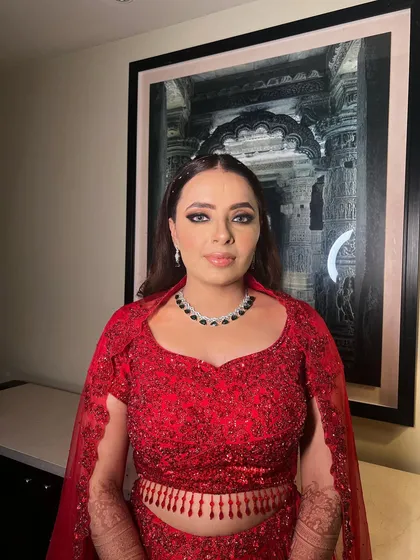 The client looking stunning in her red reception outfit. The sleek half-updo is modern and chic.
