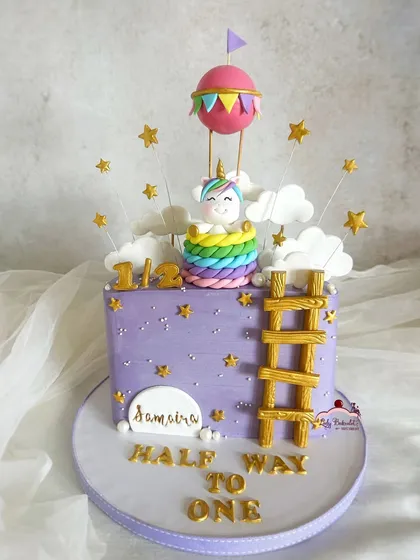 A magical half birthday cake! This design features a unicorn in a hot air balloon, climbing a ladder to the stars.