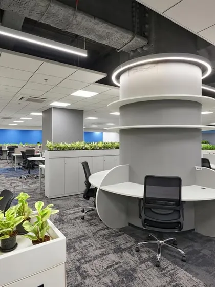 This workspace is organized around a central column that has been transformed into a circular, multi-user workstation. Planters are integrated throughout the space to improve air quality and aesthetics.