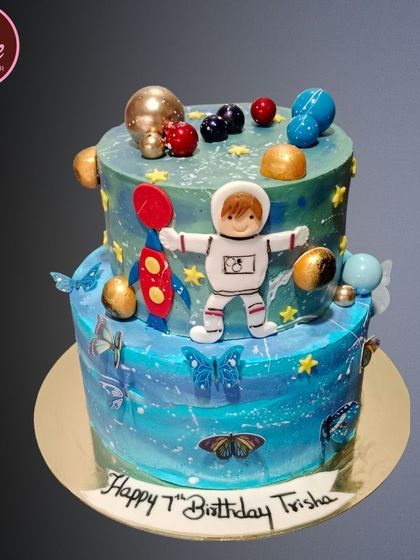 A creative fusion cake combining a space theme with butterflies. This two-tiered galaxy cake features an astronaut, planets, and delicate butterflies for a unique design.