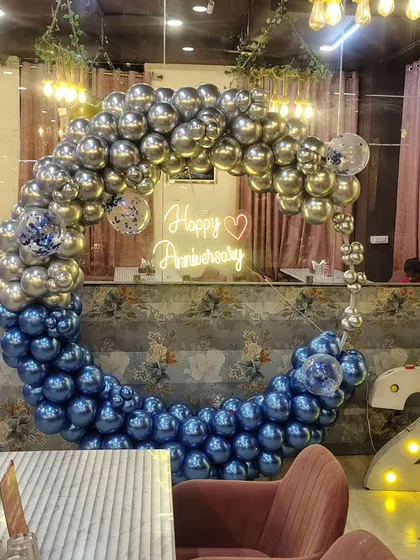 A chic anniversary celebration at a restaurant. We created this beautiful balloon ring using chrome blue and silver balloons, with a "Happy Anniversary" neon sign in the center.
