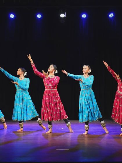 The full line of Sāttvatī dancers on stage, their arms extended in a graceful pose that captures the expansive nature of our group performances.