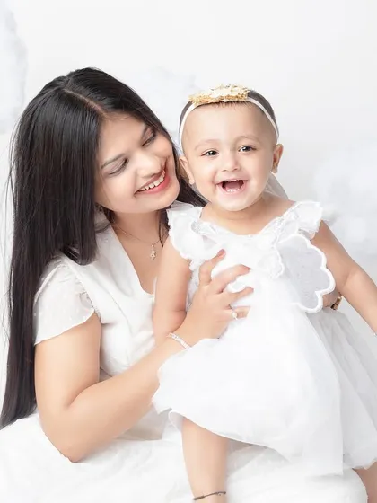 A candid moment of laughter between mother and daughter during their angel-themed photoshoot.