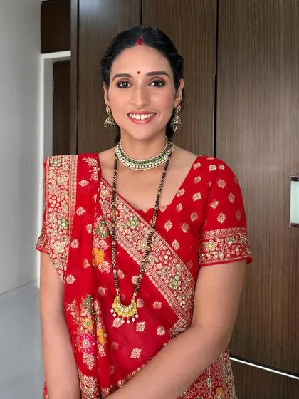 A classic festive look created for a Karwachauth celebration. The makeup features soft smokey eyes, a traditional red bindi, and a radiant complexion that complements the bright red saree.