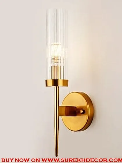 A super royal wall lamp with a golden lush finish. The design features a fluted glass shade on a pointed brass rod, exuding a sense of classic luxury and sophistication.