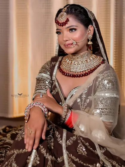 A seated portrait of the bride, showcasing the intricate jewelry and the detailed work on the brown lehenga.