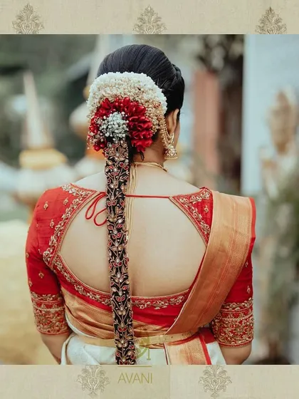 A classic red bridal blouse with a teardrop-shaped back opening. The entire back and sleeves are heavily embroidered, showing the rich detail I bring to traditional South Indian wedding attire.