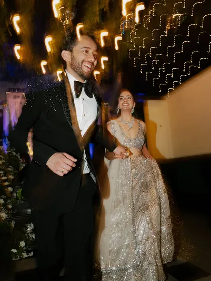 A candid, motion-filled shot of the couple making their entrance. The blur of lights and movement captures the exhilarating rush of the Sangeet night.