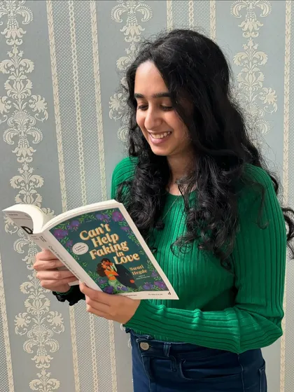 A photo from my October photo dump, reading an ARC of *Can't Help Faking in Love*. It was such a good month, full of exciting career news.