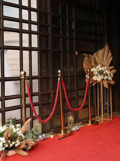A close-up of the red carpet entrance decor, with gold stanchions and floral pieces that combine boho and glam elements.