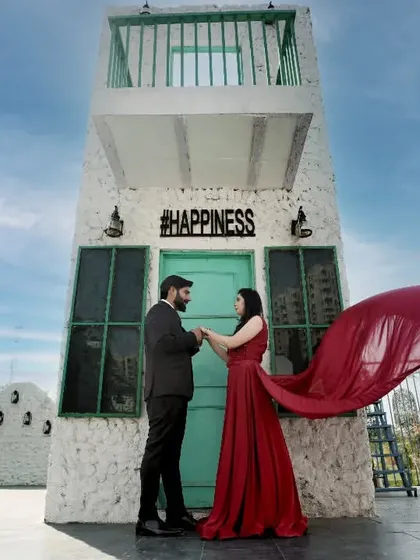 A dramatic shot in front of a building with a "#HAPPINESS" sign. The flowing red fabric adds movement and a pop of color.