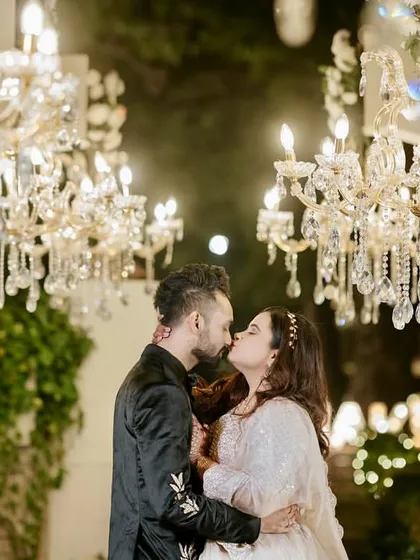 A romantic kiss under the chandeliers. The warm glow of the lights creates a magical and intimate atmosphere for the couple's portraits.