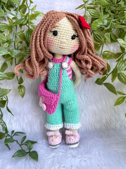This is the same doll in her second outfit! This set includes mint green overalls, a pink floral bag, and a cute red hair clip. Having multiple outfits makes playtime even more exciting.