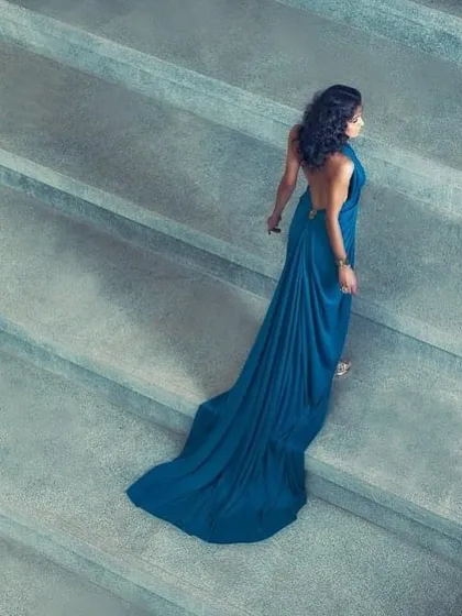 An elegant and simple shot from a personal styling session. The beauty of this image is in its minimalism, focusing on the graceful trail of a draped blue gown as the model ascends a staircase.