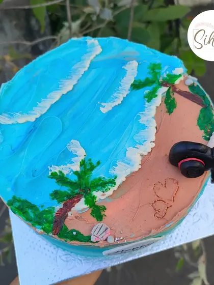 A beachy cake for someone who loves the sea and photography. This design features buttercream waves, a sandy beach, and a tiny fondant camera.