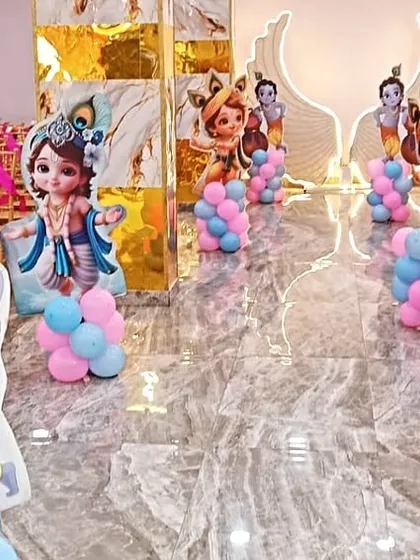 The aisle leading to the stage is decorated with Little Krishna cutouts and balloon pillars. This creates a festive pathway for guests at a naming ceremony in our Kalyan banquet hall.