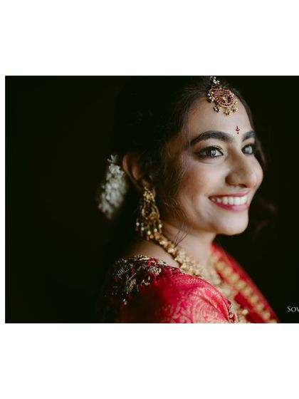 A close-up portrait of a bride, her happy smile and sparkling eyes beautifully captured. The focus is on her expression of pure joy.