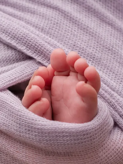 A macro shot of tiny newborn feet peeking out of the swaddle. It’s these little details that make newborn photography so special.