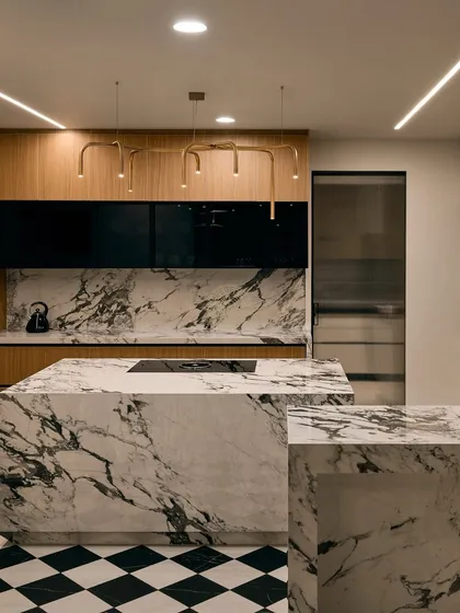 For this Bangalore kitchen, we went for a bold and classic look. A striking black and white marble island is the centerpiece, complemented by black and white checkered flooring. To add warmth, we used wood veneer cabinets and finished the space with modern gold pipe-style lights.