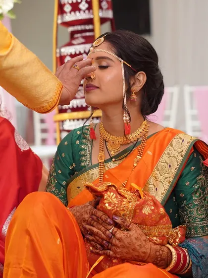 A quiet moment of blessings during the wedding ceremony. The bride's eyes are closed as she receives blessings, her makeup looking flawless and serene.