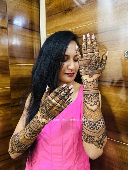A stylish pose from a bride showing off both her intricate mehendi-adorned arms.