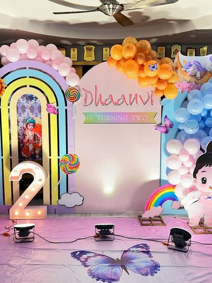 A magical unicorn and rainbow theme for a second birthday, with character cutouts, pastel balloon clouds, and a light-up number '2'.