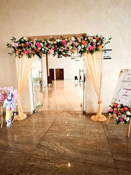 The entrance to the naming ceremony for Adhokshaj, featuring a floral arch, draped curtains, and a personalized welcome sign.