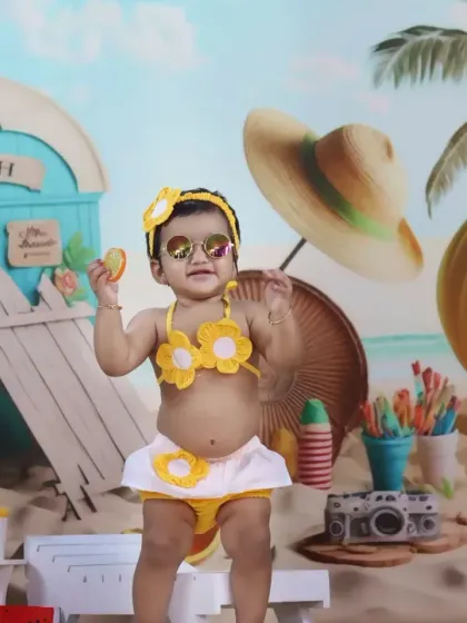 A stylish baby girl poses in a yellow bikini and sunglasses, looking like a true beach fashionista.