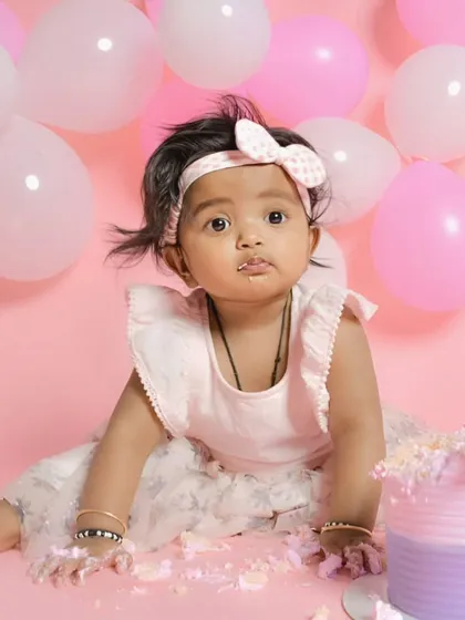 This adorable baby is having a great time during her cake smash session. Her cute expression and cake-covered hands perfectly capture the messy joy of this fun milestone.