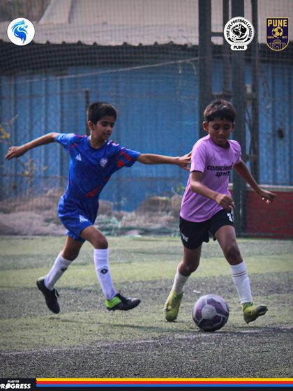 A player on the dribble, fending off a challenge from a defender. This is grassroots football at its most exciting.