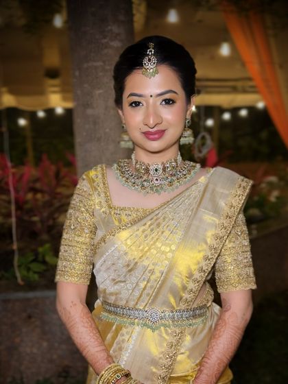 A full-length shot showing the elegance of the gold saree and the bride's graceful posture.