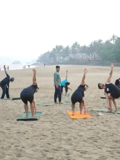 Guiding the group through a Revolved Triangle Pose. Beach yoga is more than movement; it's about feeling the salty breeze and soft sand as you connect with your body and the elements.