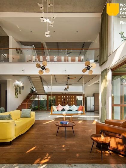 Sunlight streams into the open-plan living area, illuminating the wooden floors and the traditional indoor swing.