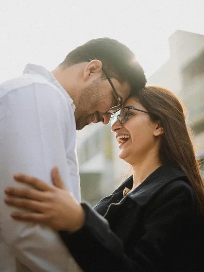 A close-up of a couple sharing a laugh, their heads together against the light. These are the authentic, heartfelt moments we aim to capture.