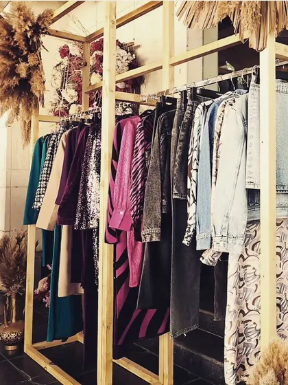 A custom-built wooden clothing rack decorated with dried florals, designed to display the new collection. This functional piece was integrated into the overall boho-chic decor of the launch event.