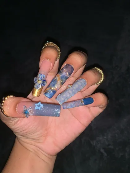 A close-up of the 3D floral and star embellishments on the water-themed nails.