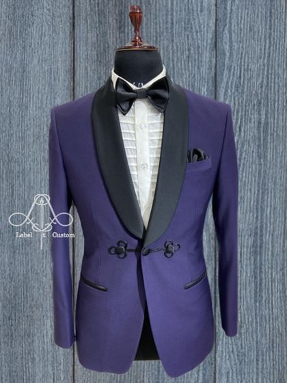A royal purple tuxedo jacket with a unique frog closure detail. This small but distinctive element adds a touch of bespoke character to the classic shawl collar design.