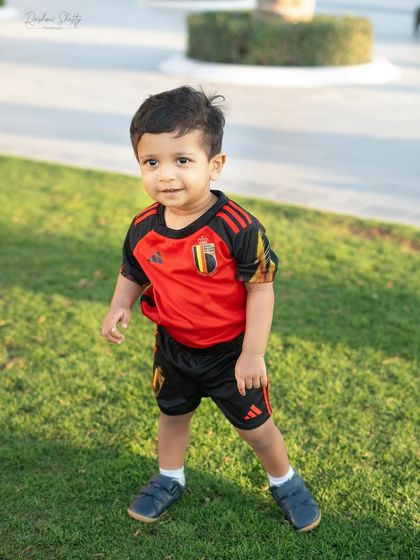 A full-length shot of our little football star. The green grass and natural light make the colors of his jersey pop.
