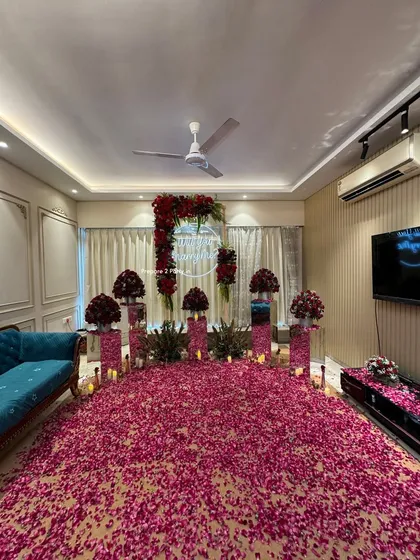 We can transform any living room into a breathtakingly romantic space. This surprise proposal decoration features a floor completely covered in thousands of red and pink rose petals, a floral arch with a custom neon sign, and elegant bouquets on mirrored pedestals.