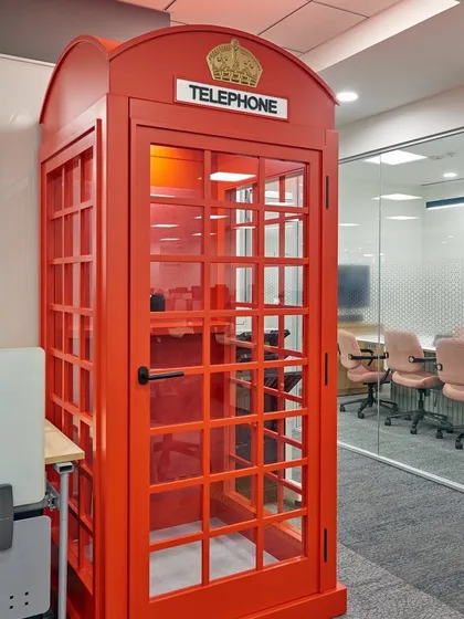 A classic red telephone booth reimagined as a private phone booth for an office. It's a fun, quirky design element that is also highly functional.