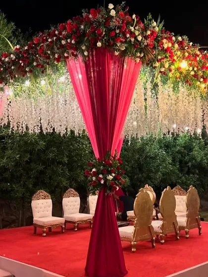 I design stunning wedding mandaps that become the heart of your ceremony. This outdoor mandap setup combines rich red and white florals with elegant draping and hanging floral strings for a truly grand and traditional feel.