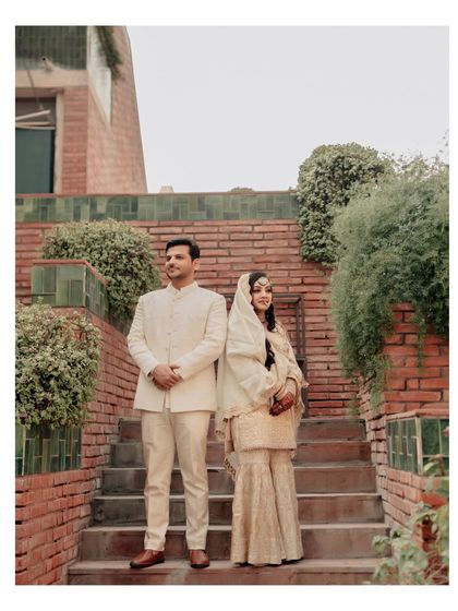 A classic full-length portrait of the couple on a brick staircase, the natural greenery and architecture providing a beautiful, rustic backdrop.